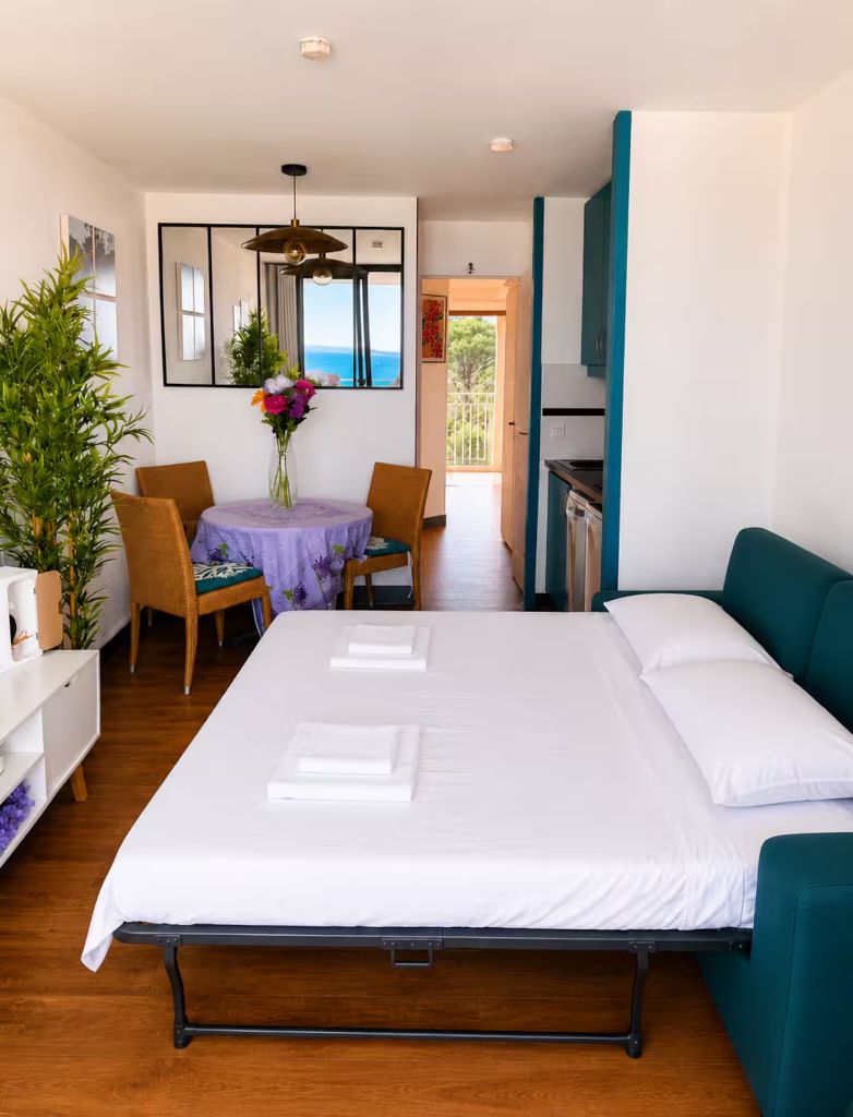 Canapé-lit du séjour déplié en couchage double, avec serviettes pliées et vue sur le coin repas