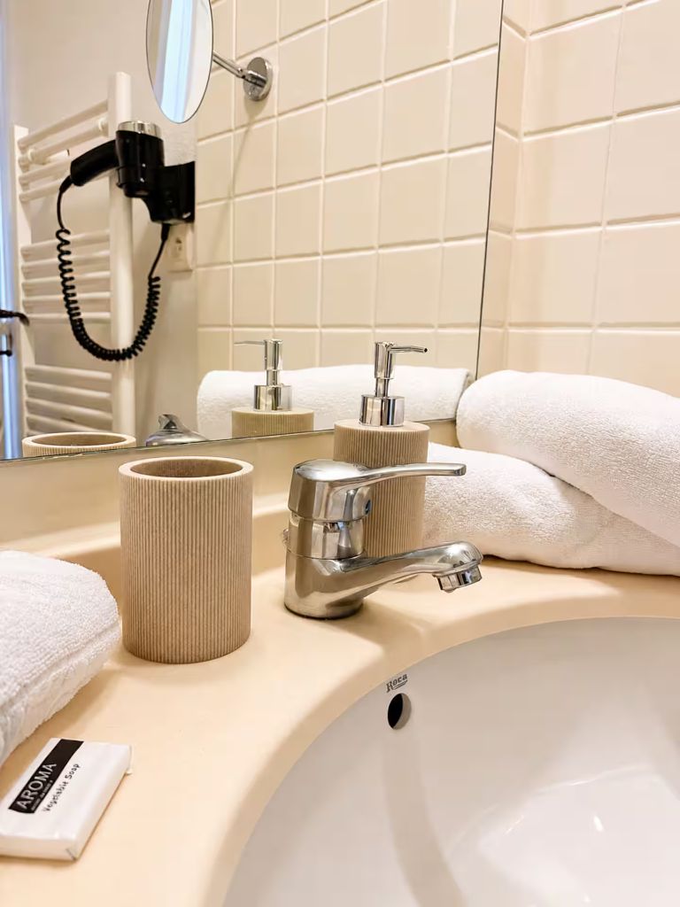 Détail du lavabo de la salle de bain avec serviettes roulées, savon et sèche-cheveux mural