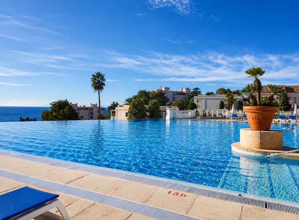 La piscine de Villa Francia et sa margelle ouverte sur la Méditerranée, bordée de palmiers