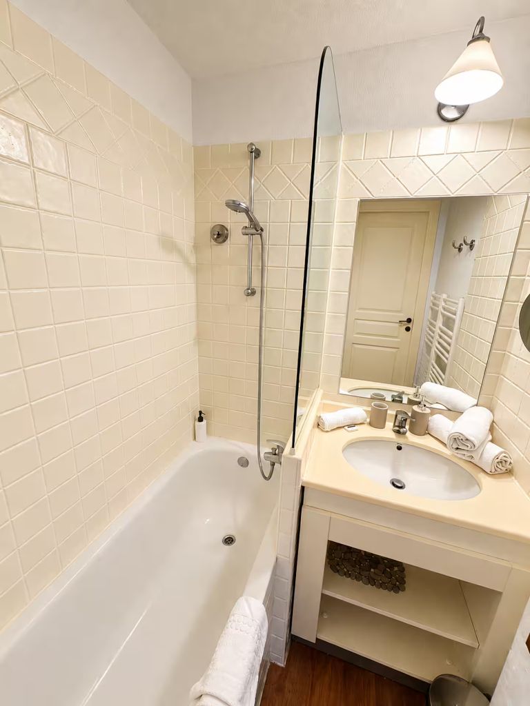 Salle de bain de Blue View Cannes avec douche, lavabo, miroir et serviettes blanches