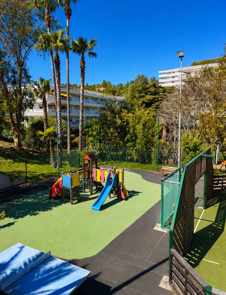 Aire de jeux pour enfants avec toboggan et balançoires, table de ping-pong et terrain clôturé dans le parc de Villa Francia