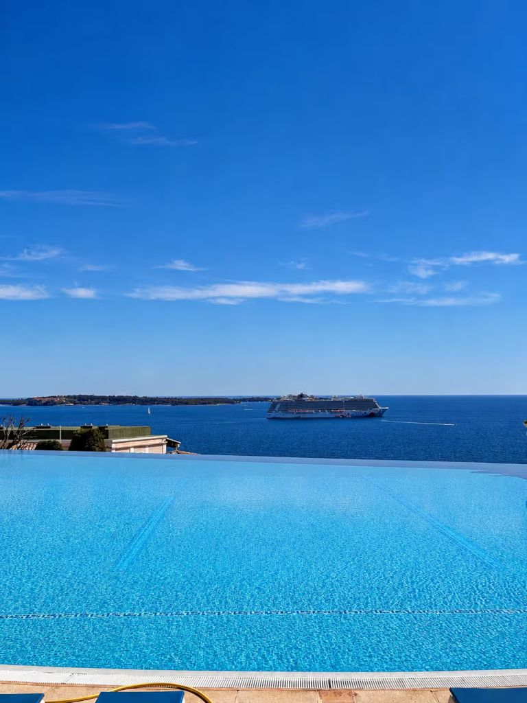 Vue depuis la piscine de Villa Francia sur la mer Méditerranée, avec un paquebot au large et les îles de Lérins