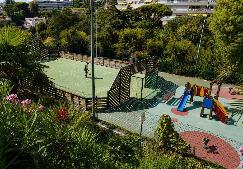 Court de tennis, terrain de sport et aire de jeux pour enfants dans le parc de la résidence Villa Francia à Cannes